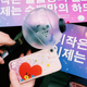 An official BTS ARMY Bomb light stick is shown. It has a black stick for a handle and a clear sphere on top.